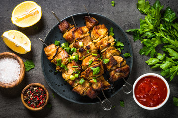 Grilled meat with herbs on black top view.
