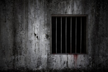 Bloody scary on the window with rusty bars on old grungy prison cell wall, concept of horror and...