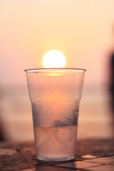 dring water in plastic glass with sunset background
