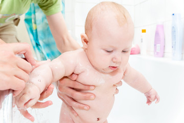 A small child in the shower, bathing a newborn girl, water procedures for a child; clean hygiene and child care.