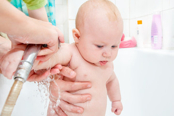 A small child in the shower, bathing a newborn girl, water procedures for a child; clean hygiene and child care.