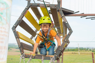 A child on the cable car in an extreme park. A boy dressed in a protective helmet and insurance, overcomes obstacles in the cable car.