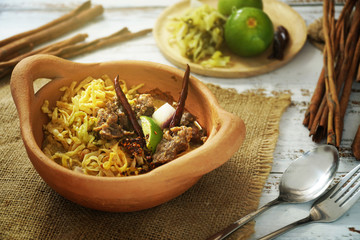 Still life photography of food: Khao Soi, Yellow noodles with beef curry served with crispy noodle and vegetables. Traditional food of Northern Thailand. Shooting in studio, Clean asian food ideas.