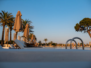 Obraz na płótnie Canvas sunbeds and umbrellas near resort's pool . Sun beds and umbrellas at the poolside