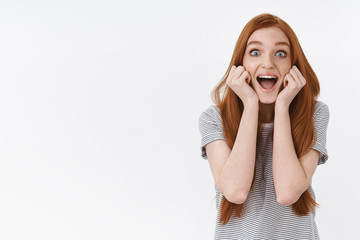 Fototapeta premium Lively amused thrilled happy young cute redhead girl popping blue eyes surprised screaming cheerfully excited see favorite popular singer standing white background amazed, attend awesome concert
