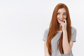 Curious intrigued lovely young romantic redhead girl blue eyes thouthfully biting finger smiling delighted imagine interesting idea thinking look upper left corner have desire, white background