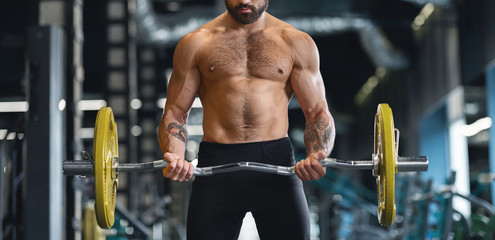 Fototapeta na wymiar Muscular man with naked torso training hard with heavy barbell