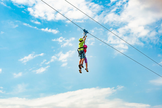 Brother and sister go down the rope in an extreme park. People with the block hold on to the rope and roll down.