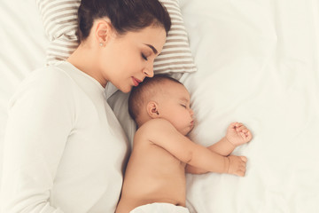 Young mom and her cute baby sleeping in bed