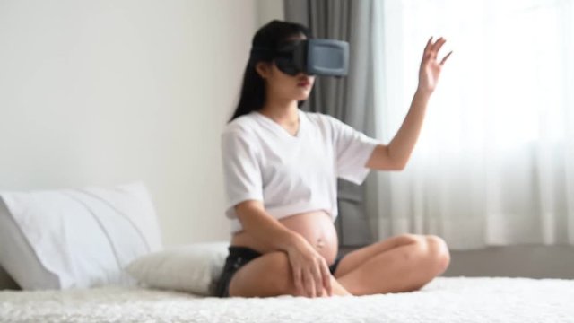 Blurred soft of the Pregnant women are using the VR box in a white bed, to technology concept.
