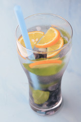 Fresh cold glass of lemonad with orange lemon,  mint leaves and ice on a blue background