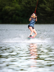 Fototapeta premium Young pretty slim woman riding wakeboard in summer 