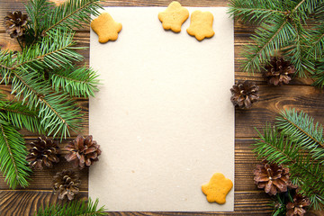 Christmas card, free space for text. Pine cones, gingerbread cookies and fir tree branches on brown table background. Vintage, old-fashion style. 