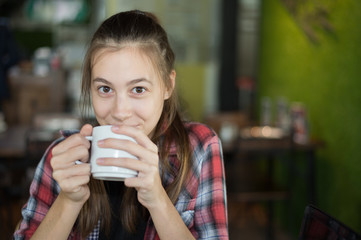 beautiful caucasian woman holding a cup of coffee in her hand at coffee shop