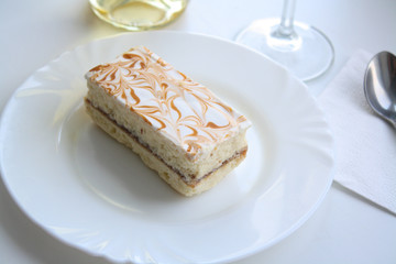 Cake on a white plate, glass and wine 