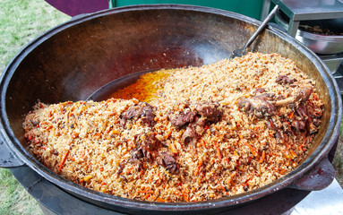 Real pilaf in a huge cauldron. Cooking national dishes. Traditional pilaf cooking.