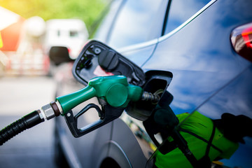 Hand refilling the white pickup truck with fuel at the gas station.