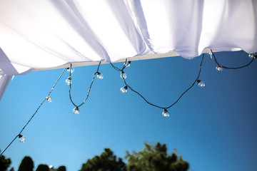 One long electric garland for lighting with white light bulbs against the background of a blue...