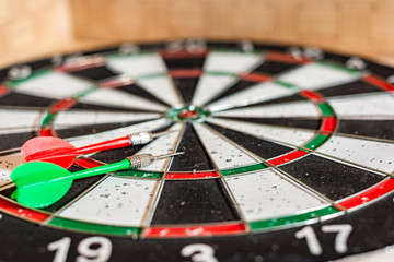 Fototapeta premium A round board for playing darts close up, green and red darts are on the target.
