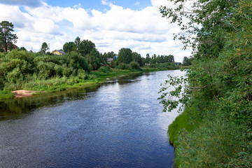 Fototapeta na wymiar Summer river village landscape. Sandy beach on bank, green grass and trees blue river and cloudy sky
