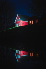 Red and white house by the river on a cloudy night