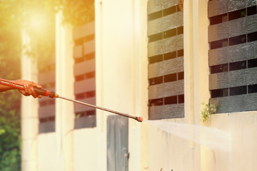 High pressure cleaning,side view..Man hand holding pipeline of high pressure cleaning machine pointing to old dirty grunge wall ,professional cleaning services .