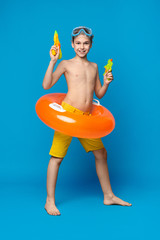 Teenage boy in swimwear standing with water guns