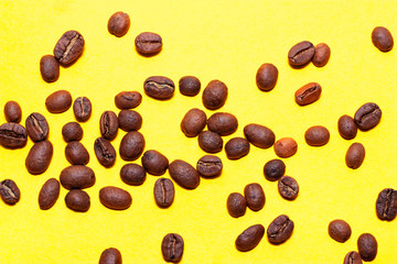 Coffee beans isolated on the yellow background. Joyful minimal coffee-theme with copy space