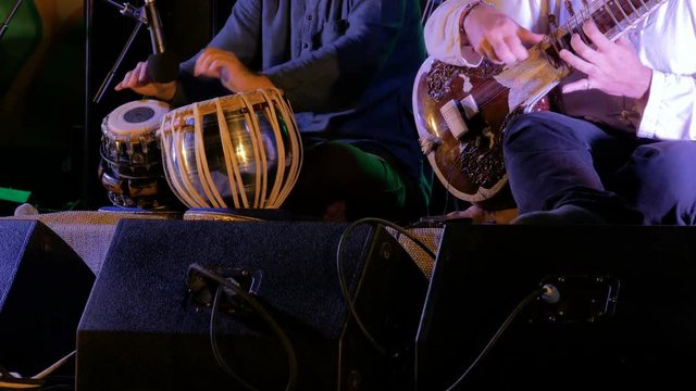 Two men playing traditional Indian tabla drums and sitar on stage of ethnic open air concert. Relaxation, meditative and traditional ethnic music concept
