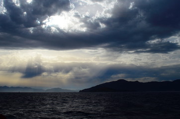 Naklejka na ściany i meble the setting sun in the clouds over the Aegean Sea