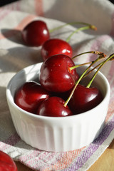 Composition of ripe juicy berries of a sweet cherry in a white cup.