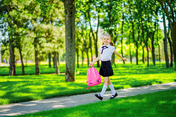 Fototapeta premium Portrait of happy Caucasian young smiling girl wearing school backpack outside the primary school. schoolgirl, elementary school student runs jumping from school, graduation, summer holidays.