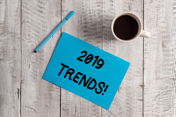 Conceptual hand writing showing 2019 Trends. Concept meaning general direction in which something is developing or changing Pastel Colour paper and pen with coffee cup on wooden table