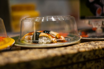 Sushi dish rides on a conveyor belt at a Japanese sushi bar.