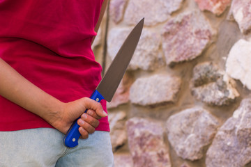 kitchen knife in girl hand behind the back willingness to violence concept picture with empty space for copy or text 