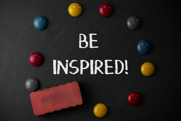 Word writing text Be Inspired. Business photo showcasing fill someone with urge or ability to do or feel something Round Flat shape stones with one eraser stick to old chalk black board