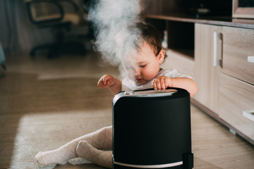 Little baby looks at the humidifier. Moisture in the house concept