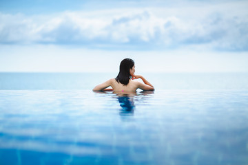 Asian woman relax in pool on beach