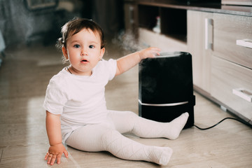 Little baby looks at the humidifier. Moisture in the house concept