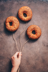 Three bagel balloon concept in the hand of a girl on a dark rustic background. Flat lay, copy space