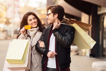 Shopping together. Woman showing credit card to husband
