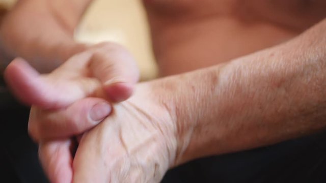Elderly Man Rubs A Painful Wrist  And Put On Wrist Support.