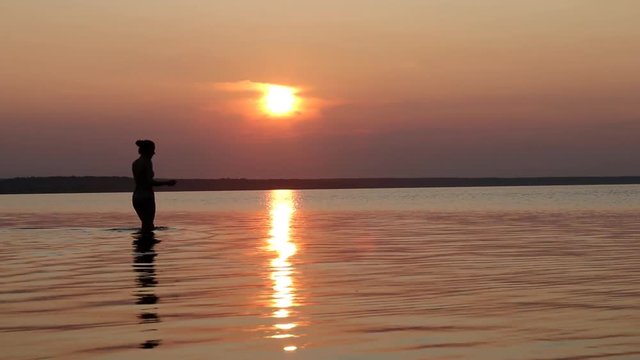 Silhouette of lovers on beach at sunset. A couple of people are photographed in the lake. Love story. Couple in love walking at sunset. Lovers on holiday.