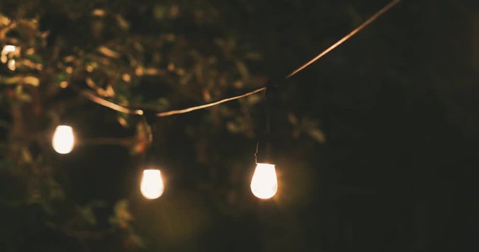 outdoor party string lights hanging on a line in backyard. dolly shot
