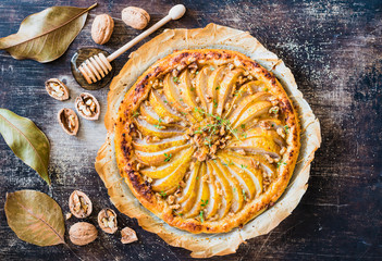 Pie with pear and nuts top view on rustic background.