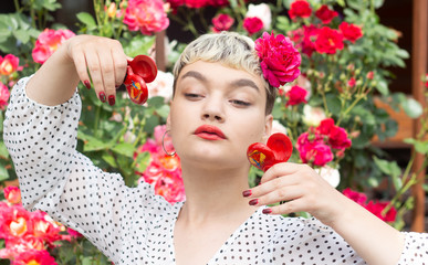 A beautiful young blonde girl in a white blouse and with a rose in her hair expresses emotions in a...