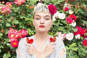 A beautiful young blonde girl in a white blouse and with a rose in her hair expresses emotions in a...