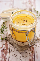 Ghee oil according to the traditional Indian recipe. Cooked with cumin and fresh herbs. Stored in a glass jar. Close up and vertical view.