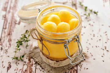 Ghee oil according to the traditional Indian recipe. Cooked with cumin and fresh herbs. Stored in a glass jar. Close up and horizontal view. .