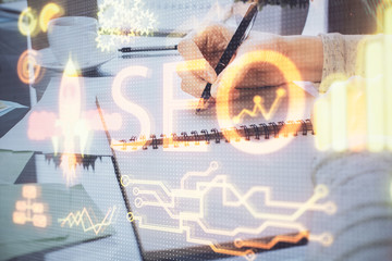 Multi exposure of woman's hands making notes with SEO icon. Concept of Search engine optimization